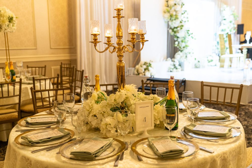 A round table set in ivory and gold around a candelabra and white floral centrepiece