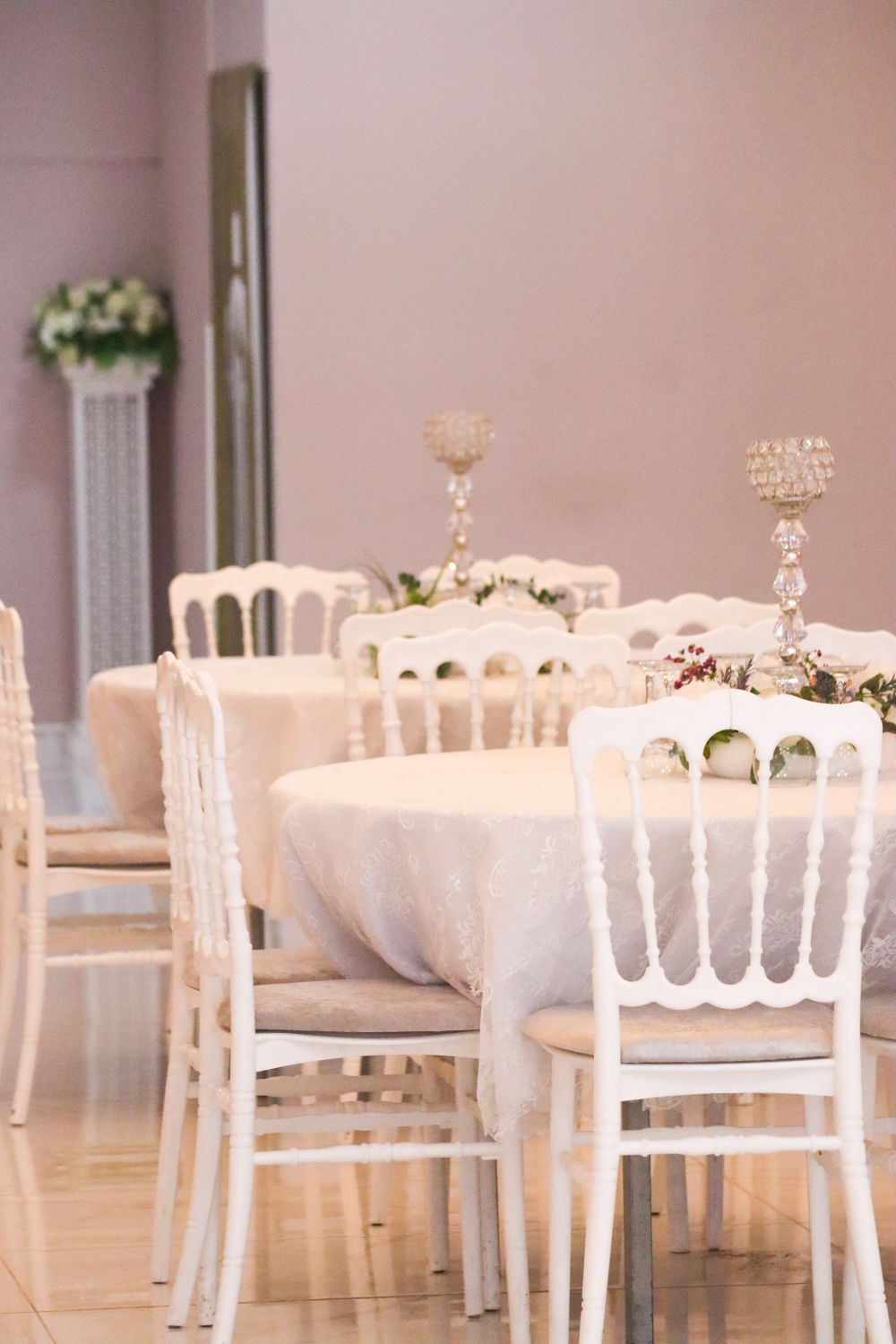 Round tables dressed in white with matching chairs and tall candelabra