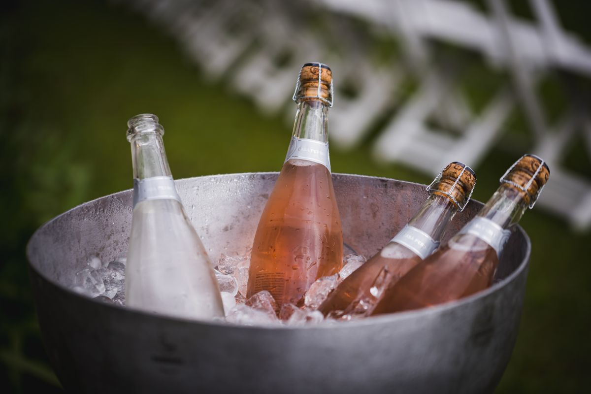 Bottles chilling in a large metal bucket of ice at an outdoor event